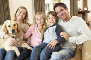 Happy young family sitting on sofa holding a dog